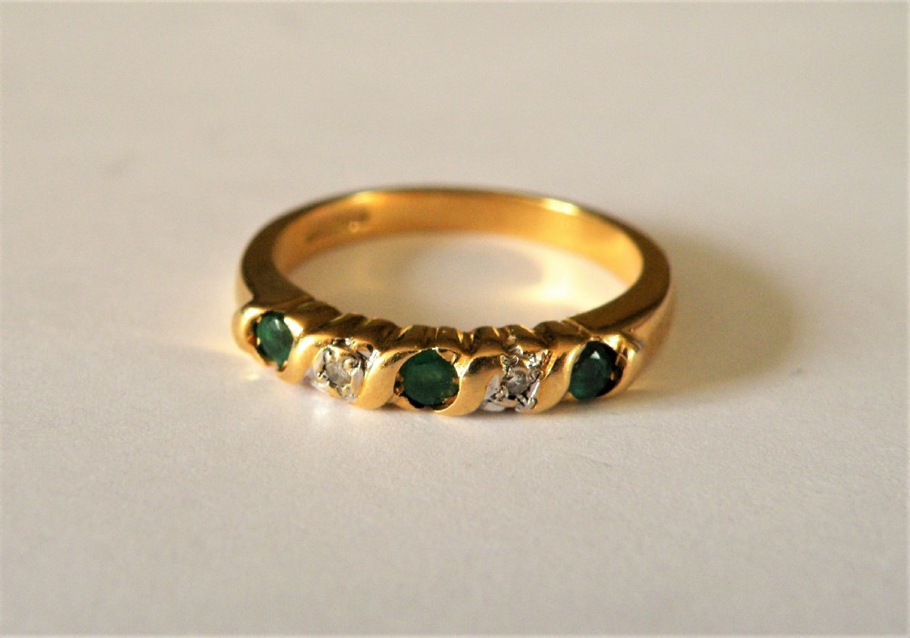 an emerald and diamond half hoop ring set in 18 carat gold