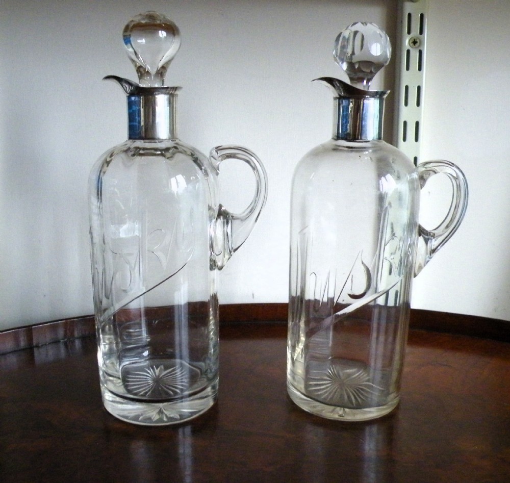 a good pair of 1905 edwardian silver and glass whisky jugs